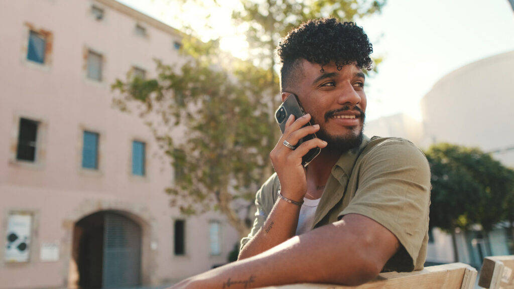 young man talking on the phone while sitting outside